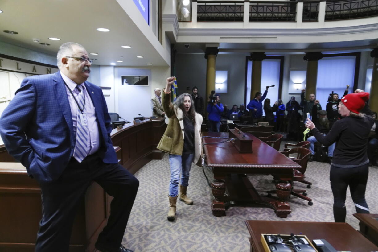 Mimi German, center, and, Star Stauffer, right, disrupt the Portland City Council meeting to protest Mayor Ted Wheeler&#039;s performance regarding police tactics related to protests, people of color, and homeless issues, in Portland, Ore. The City Council approved an emergency ordinance Wednesday that will allow the city to eject disruptive protesters and ban them from council chambers for up to 60 days in some cases.