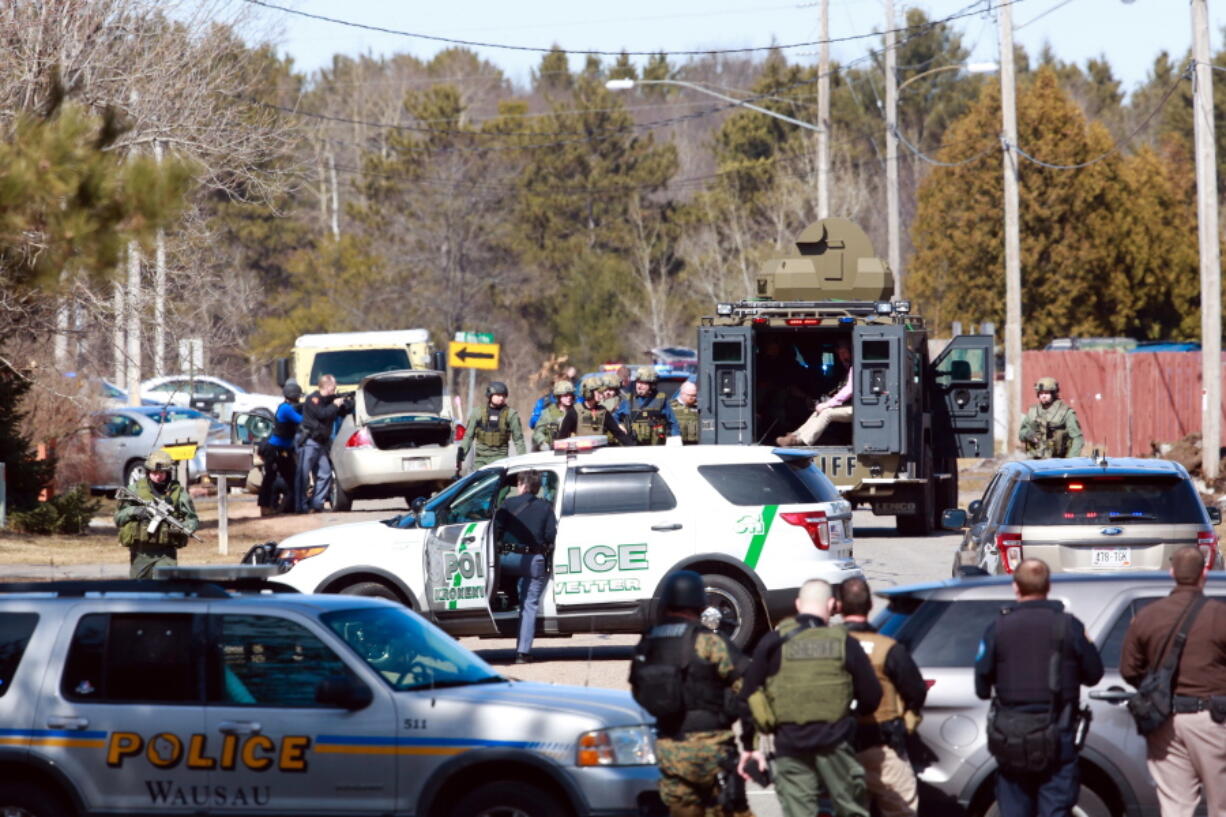 Numerous law enforcement vehicles and SWAT teams respond to shooter Wednesday, March 22, 2017, at an apartment complex in Rothschild, Wis. The shootings happened at a bank, a law firm and an apartment complex, where officers, including a SWAT team, were in a standoff with the suspect late in the afternoon, Wausau police Capt. Todd Baeten said at a news conference. The area is about 90 miles west of Green Bay.