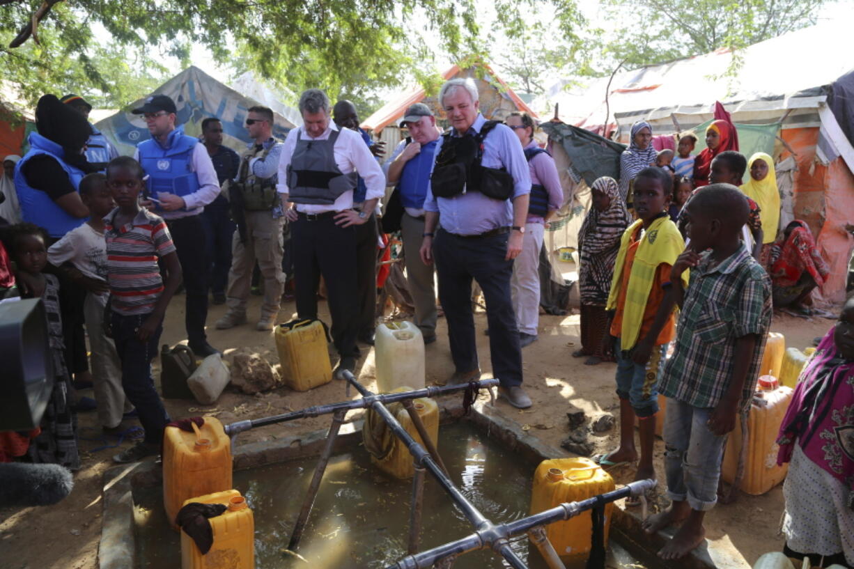 UN Humanitarian Chief Stephen O&#039;Brien, center in black bullet proof vest, meets with drought affected people as they fetch water in one of Mogadishu IDP camps in Somalia on Monday during his visit to Somalia.