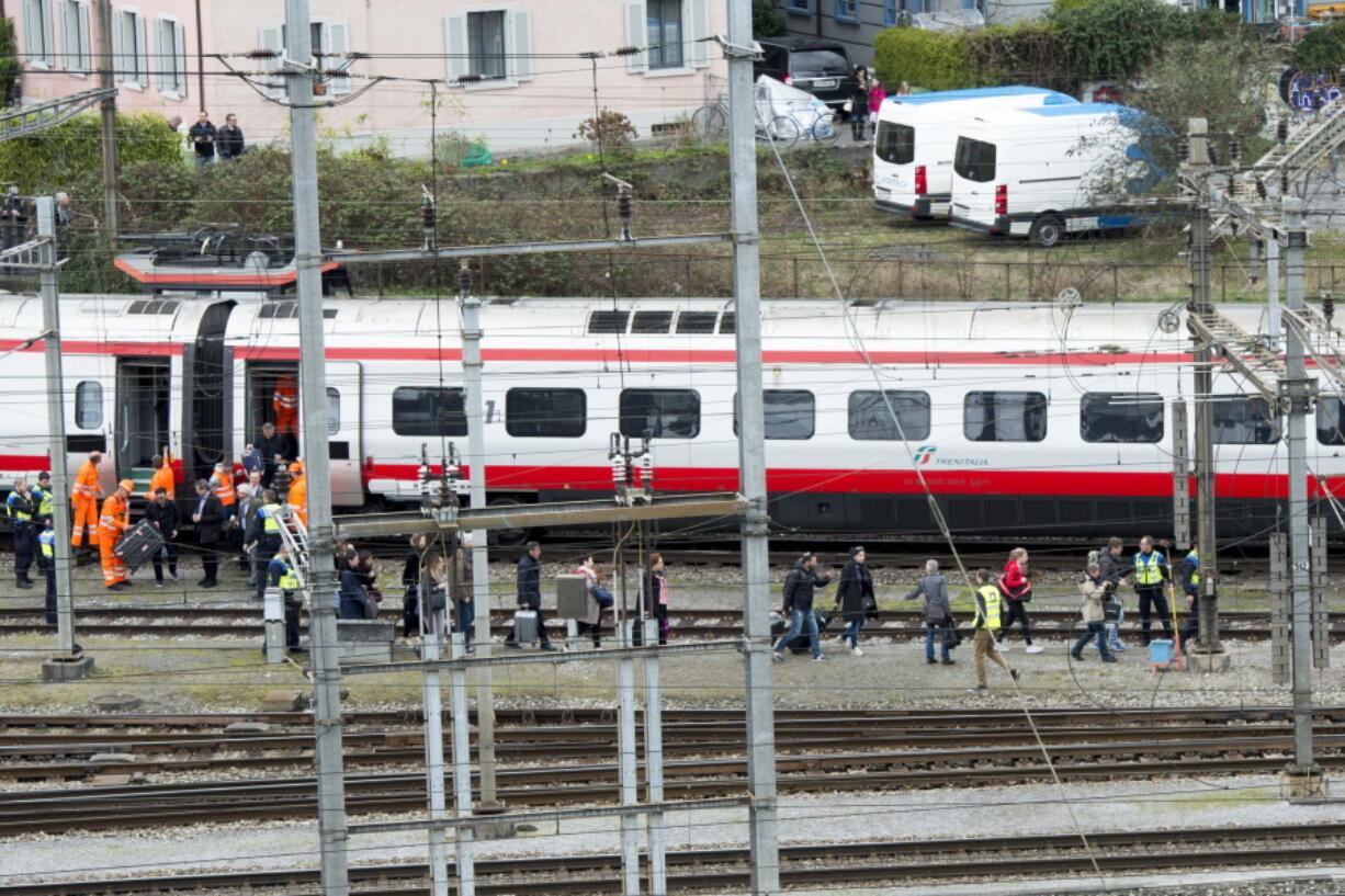 Rescuers help passengers next to a derailed train Wednesday at the station in Lucerne, Switzerland.