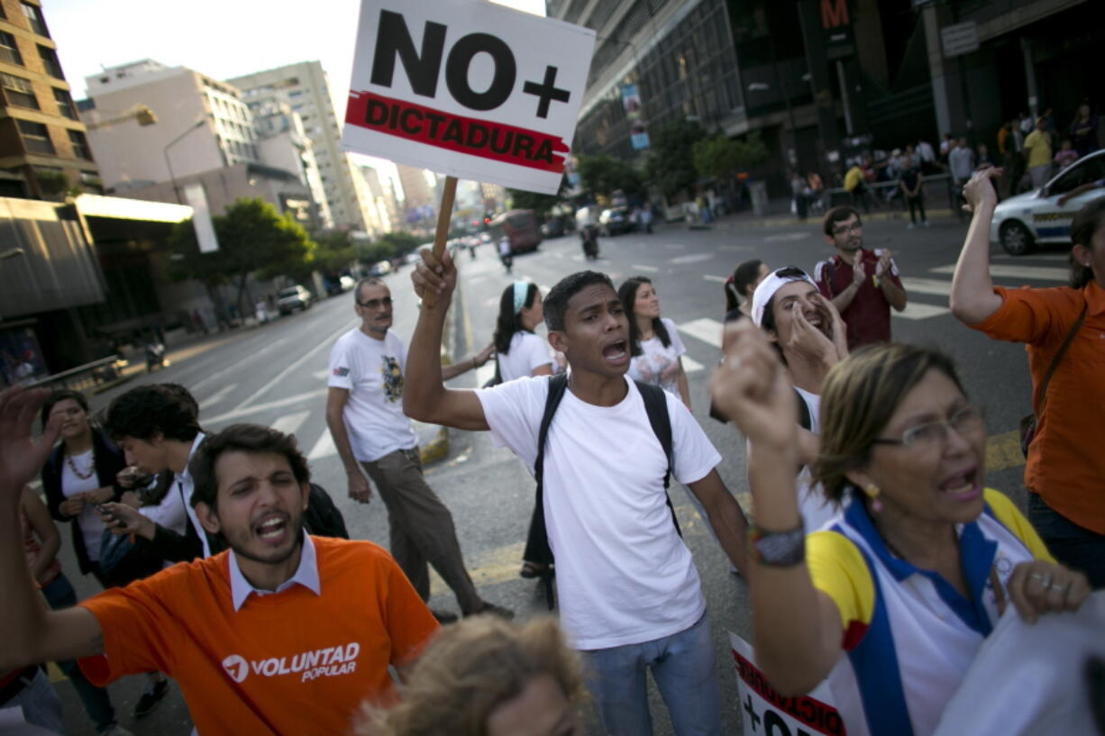 A man carries a sign that reads &quot;No more dictatorship,&quot; during a protest Friday in Caracas, Venezuela.