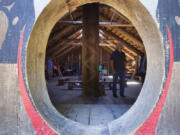 Seen through the circular front entry, a visitor looks around inside the Cathlapotle Plankhouse.