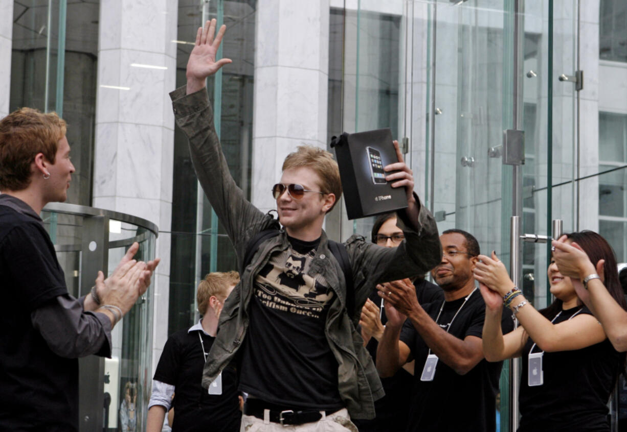 Apple employees cheer as an excited customer leaves the Apple Store with his iPhone June 29, 2007, in New York.