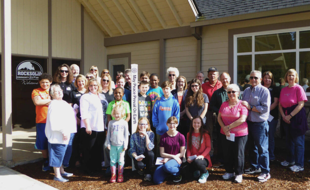 Clark County: Members of the Lewis River Rotary Club and kids from the Rocksolid Teen Community Center pose with a Peace Pole the Rotary planted, one of three they put up around Battle Ground recently.