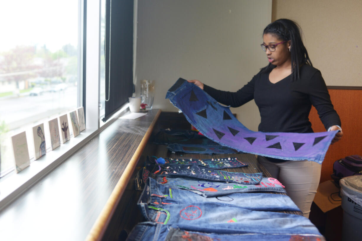 Alayah Willis, 13, holds a pair of jeans she decorated as part of the blue jean project at the Boys &amp; Girls Clubs O.K. Clubhouse. She said she painted triangles because they looked cool.