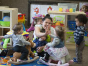 Teacher Linda Martinez shares a high-five while working with toddlers at Children&#039;s Village-Burton Road in Vancouver.