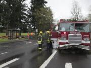 Crews work to clean up a large tree, left, after it fell on a Vancouver firetruck on East Mill Plain Boulevard following a windstorm Friday.