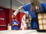 Wy&#039;east seventh-graders Nicholas Murray and Brittney Meyer nervously watch teammate Zinnia Hawthorn use a prosthetic arm the three designed to compete in an object removal challenge at the Firstenburg Student Commons at Washington State University Vancouver on Saturday.