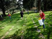 A group of volunteers lay daffodils on graves Sunday at Evergreen Memorial Gardens.