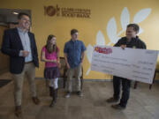 Clark County Food Bank communications manager Matt Edmonds, left, and executive director Alan Hamilton, right, look over an oversized check as it is presented by Erin Ryan, 13, second from left, and her brother, Aidan Ryan, 17, at the food bank. Edmonds and Hamilton said it&#039;s unusual for individuals, especially children, to head such a large fundraising effort.