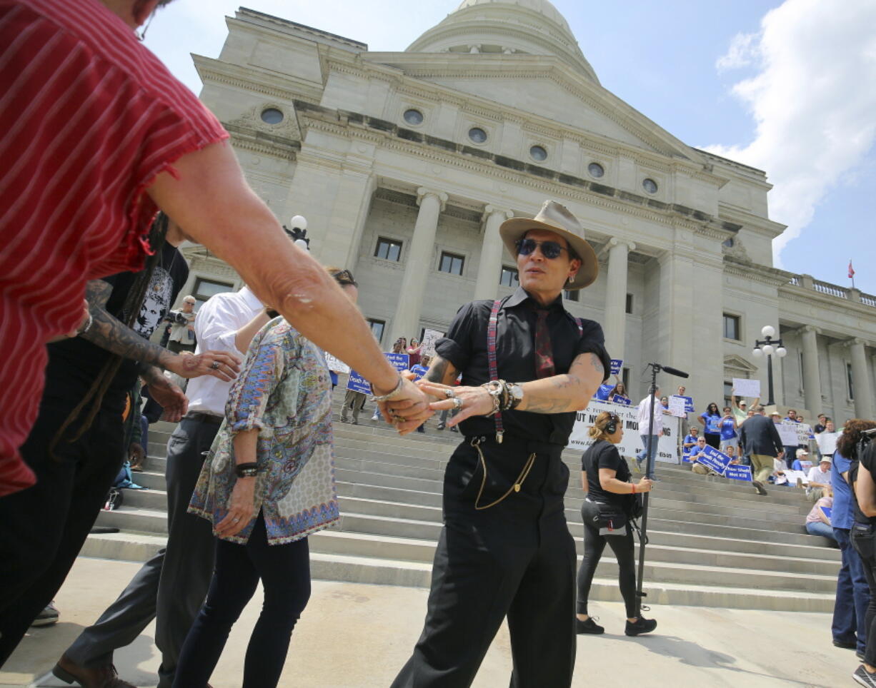 Actor Johnny Depp greets someone as he walks to the podium to speak at a rally opposing Arkansas&#039; upcoming executions, which are set to begin next week, on the front steps of the Capitol Friday in Little Rock, Ark. (Stephen B.