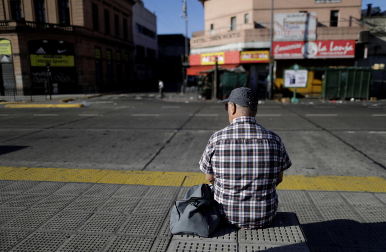 A man sits at the bus stop in a deserted station Thursday in Buenos Aires, Argentina.