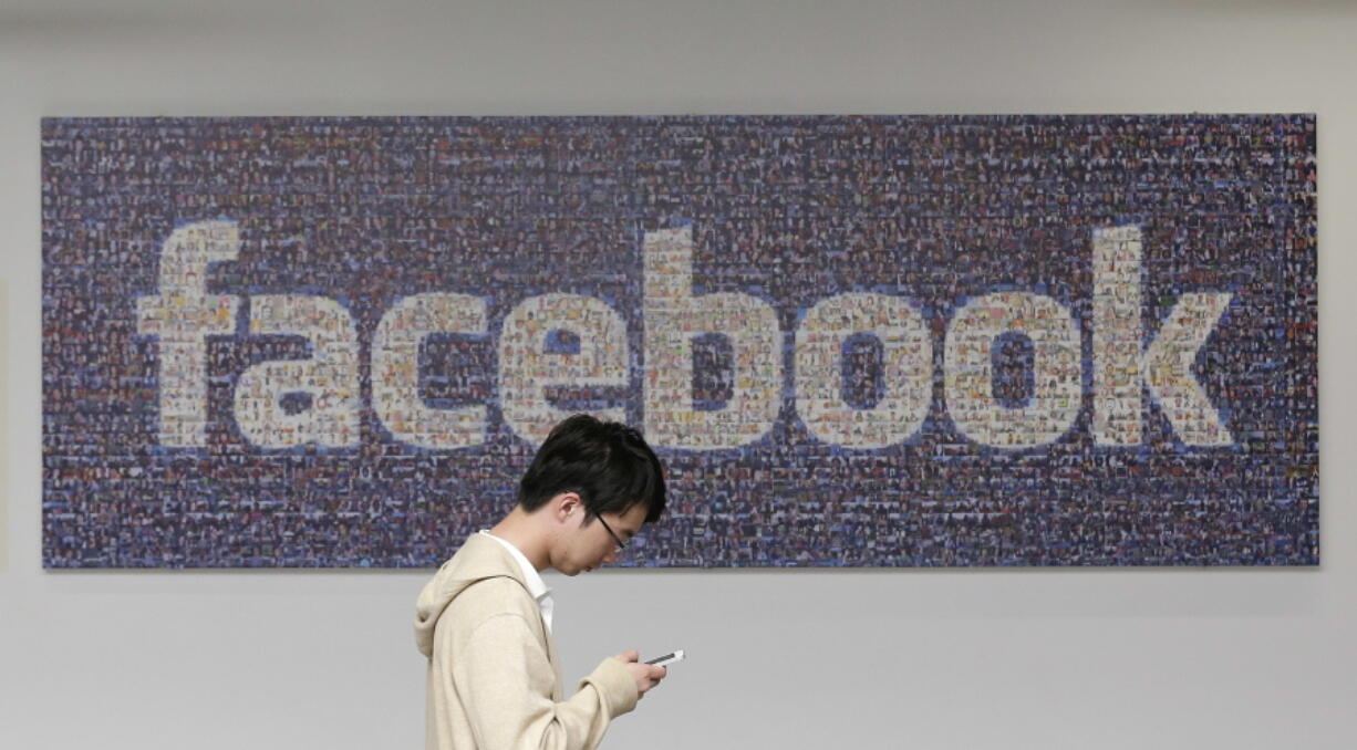 A man walks past a Facebook sign in an office on the Facebook campus in Menlo Park, Calif.