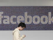 A man walks past a Facebook sign in an office on the Facebook campus in Menlo Park, Calif.