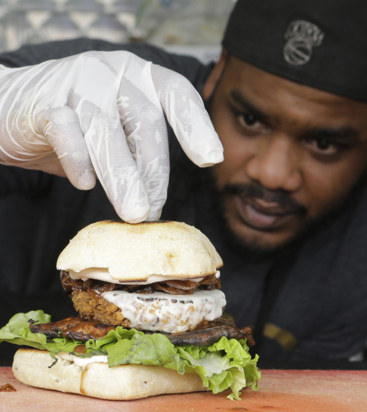 Chef Miguel Navarro inspects a Le Bleu hamburger, made with caramelized onions and blue cheese on top of portobello mushroom and lettuce, March 1 at the Atlas Meat-Free Delicatessen in Miami. When Ryan Bauhaus first started experimenting with faux meats, he fixated on recreating that subtle blood taste, settling on a tomato paste blend to mimic the acidic, iron flavor. The fatty part of meat was also not to be forgotten. Bauhaus boiled down mushrooms until he got the desired gelatinous, rubbery fat found on the back of a roast.