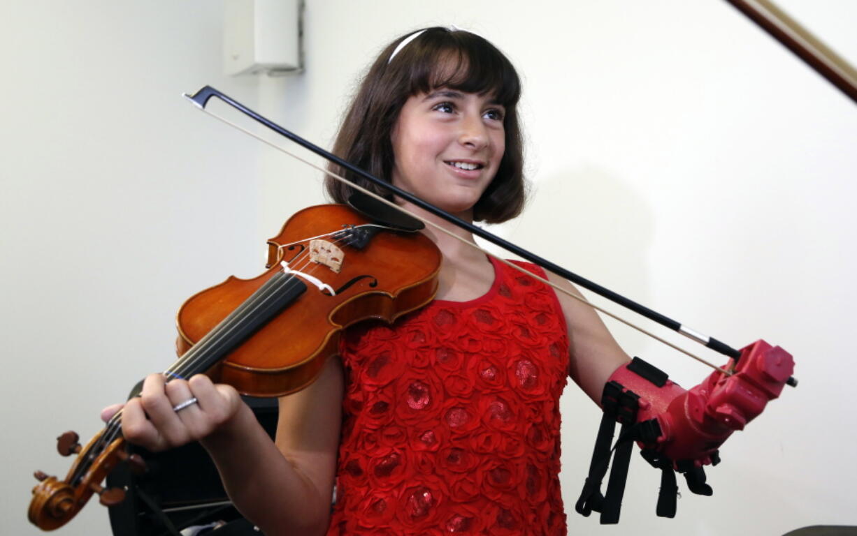 Isabella Nicola Cabrera, 10, plays her violin with her new prosthetic Thursday at the engineering department of George Mason University in Fairfax, Va. &quot;Oh my gosh, that&#039;s so much better,&quot; Isabella said as she tried it out.