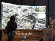 Sean Askay, right, engineering manager with Google Earth, demonstrates new features on Google Earth, displayed in background, on April 18 in New York.