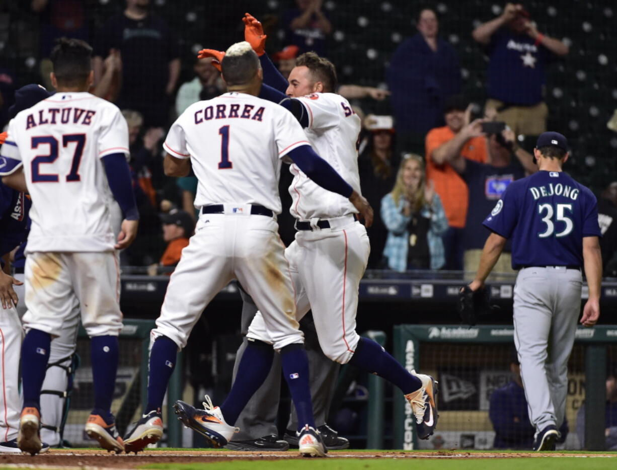 Houston Astros&#039; George Springer, front right, is mobbed by teammates after hitting the game-wining three-run home run off Seattle Mariners relief pitcher Chase DeJong (35) during the 13th inning of a baseball game, Wednesday, April 5, 2017, in Houston.