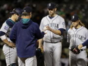 Seattle Mariners starting pitcher James Paxton, center, is pulled from the baseball game by manager Scott Servais during the fifth inning against the Oakland Athletics, Thursday, April 20, 2017, in Oakland, Calif.