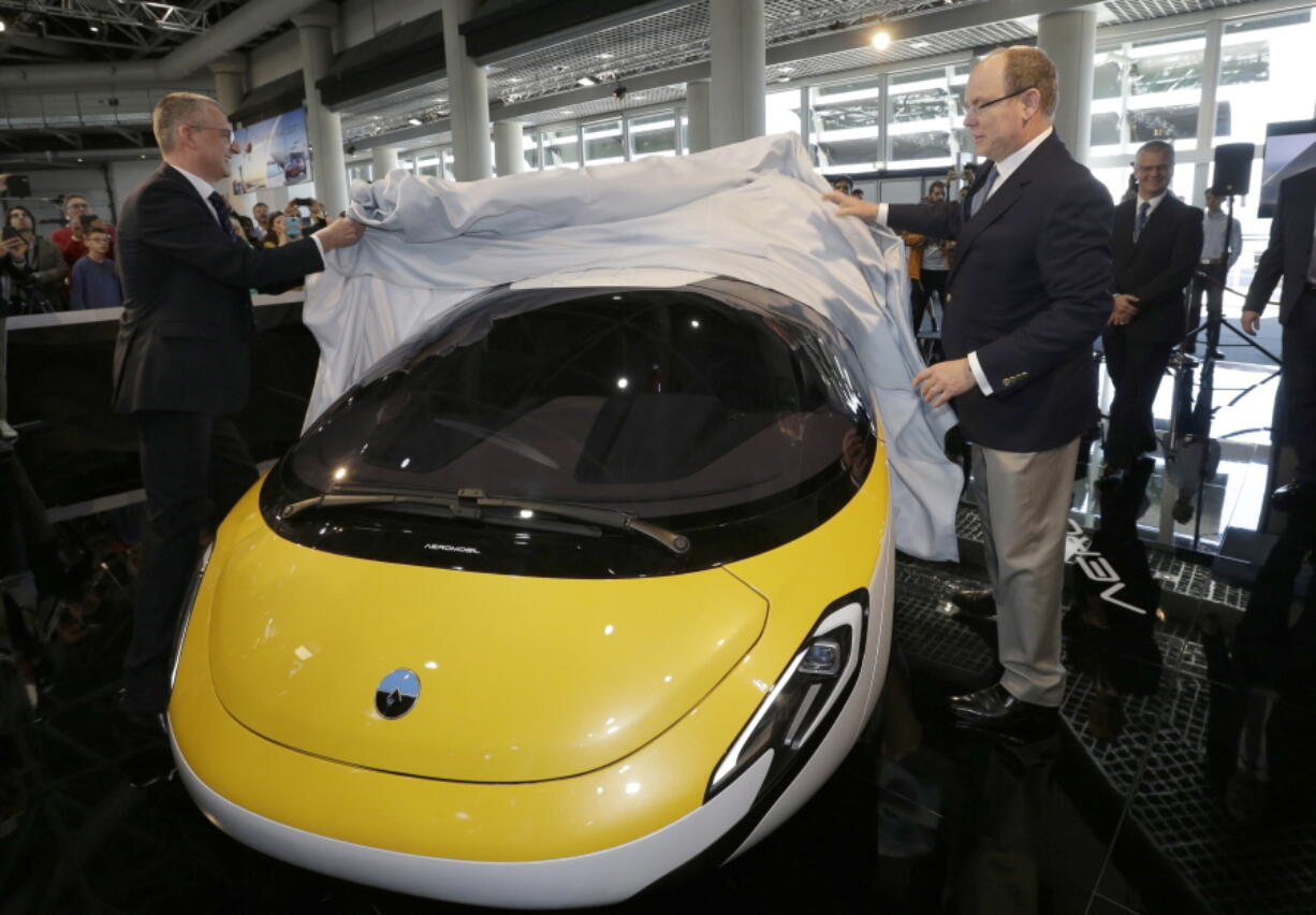 Prince Albert II of Monaco, right, and Juraj Vaculik, CEO and co-founder of AeroMobil, unveil the latest prototype of a flying car, in Monaco, on Thursday. The light frame plane whose wings can fold back, like an insect is boosted by a rear propeller. The company says it is planning to accept first preorders for the vehicle as soon as later this year.