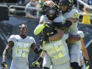 Oregon's Darren Carrington II, center right, is congratulated by teammates Kani Benoit (29) Darrian McNeal, top right, after Carrington's third touchdown during Oregon's spring NCAA college football game at Autzen Stadium in Eugene Ore., Saturday, April 29, 2017.