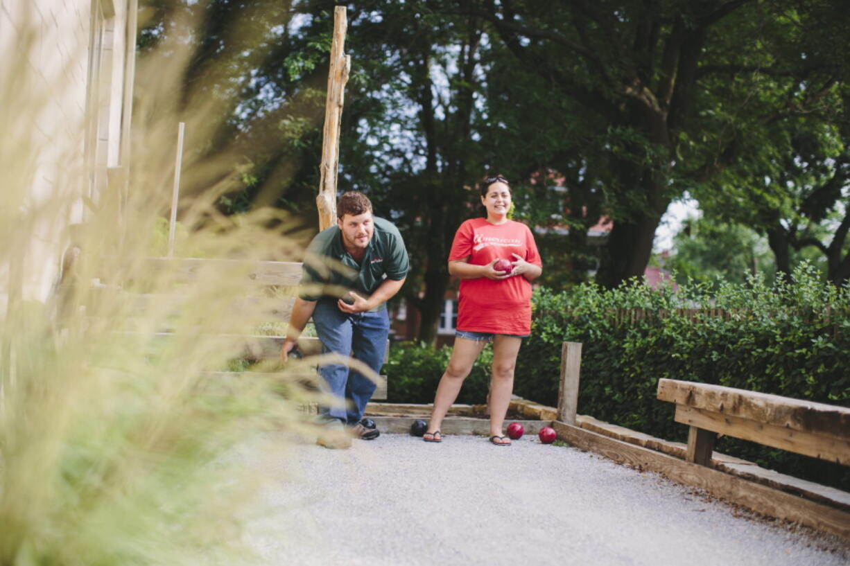 Jerrod and Paige Combs play bocce at a backyard party in Omaha, Neb. The home features this decomposed granite chip bocce court with reclaimed cedar side boards.