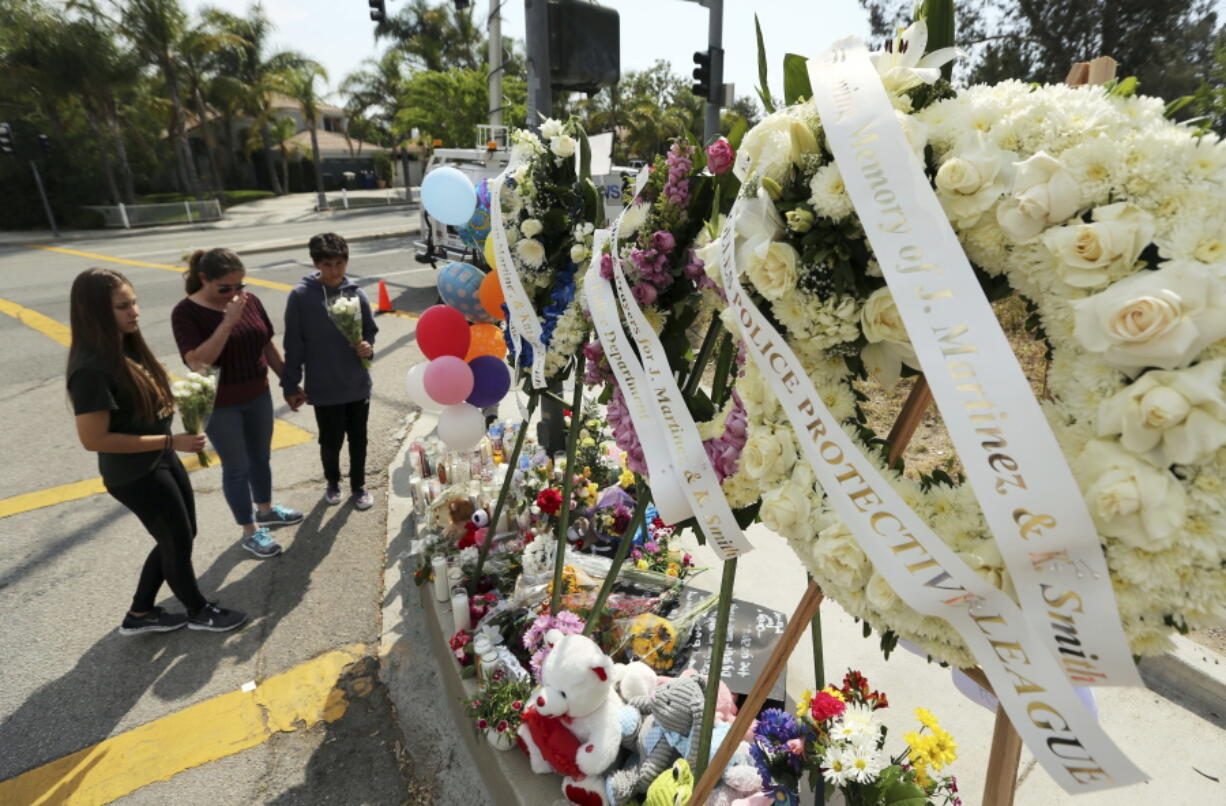 People pray before placing flowers at a sidewalk memorial to the teacher and student who were shot to death Monday at North Park Elementary School in San Bernardino, Calif., on Tuesday.