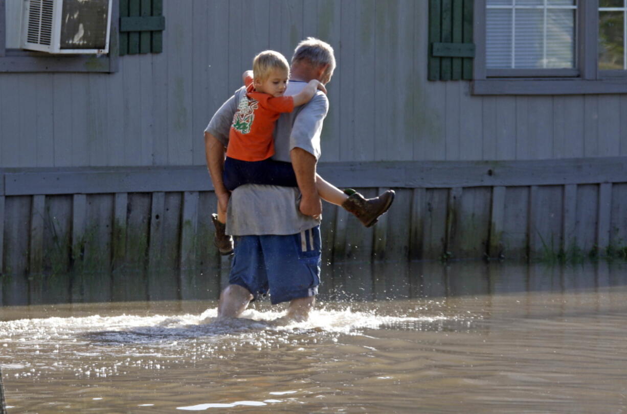 Jay Kilgore wades through floodwaters while carrying his son Casen Kilgore, 5, near the family&#039;s mobile home Monday in Pelahatchie, Miss., after severe storms dropped significant amounts of rain over the weekend. (Rogelio V.