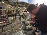 A worker puts the final touches on a New England section of Gulliver’s Gate, a miniature world depicting hundreds of landmarks, settings and events, in Times Square.