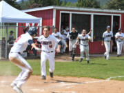 The King's Way Christian baseball team spills out of the dugout after Damon Casetta-Stubbs slides home with the winning run against Cascade Christian.