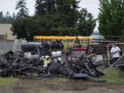 A school bus, top, passes Covington Middle School as the charred remains of a structure in Orchards are seen nearby Thursday morning.