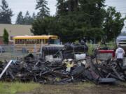 A school bus, top, passes Covington Middle School as the charred remains of a structure in Orchards are seen nearby Thursday morning.