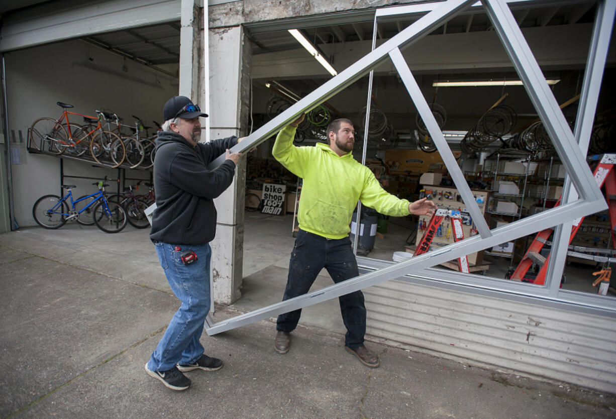 Jason Sheffield, left, and Alex Braman of River City Glass prepare to install front windows for Bike Clark County.