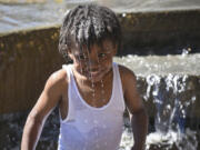 Damarius Jerman, 4, looks up at his grandmother Wednesday after dumping water on his head in the water fountain at Esther Short Park in downtown Vancouver.(Ariane Kunze/The Columbian)