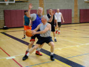 John Reinhardt fakes a pass during an Over the Hill league basketball game Monday in Battle Ground. Reinhardt and other members of the league were honored this week for their actions rendering first aid to a teammate — George Tierney, who collapsed during a game last month — which helped save his life.