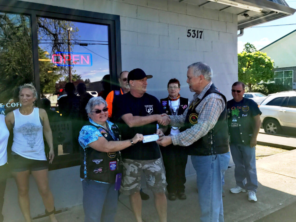 Spyder Ryders Treasurer Joyce LaFlam, left, and President William Pyne, right, present Jeff Talbott of Kleen Street Recovery Cafe with a check for the cafe’s work with the homeless.