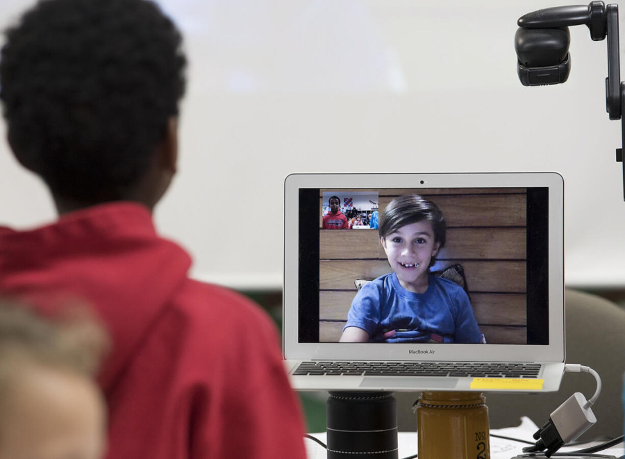 Cape Horn-Skye Elementary School second-grader Deacon Nichols, 8, left, talks to classmate Zylus Italiano, 7, who is currently in Nepal with his family as part of a 180-day trip around the world. Zylus is keeping up with his studies while traveling, doing 2 1/2  to 3 1/2  hours of schoolwork every day.