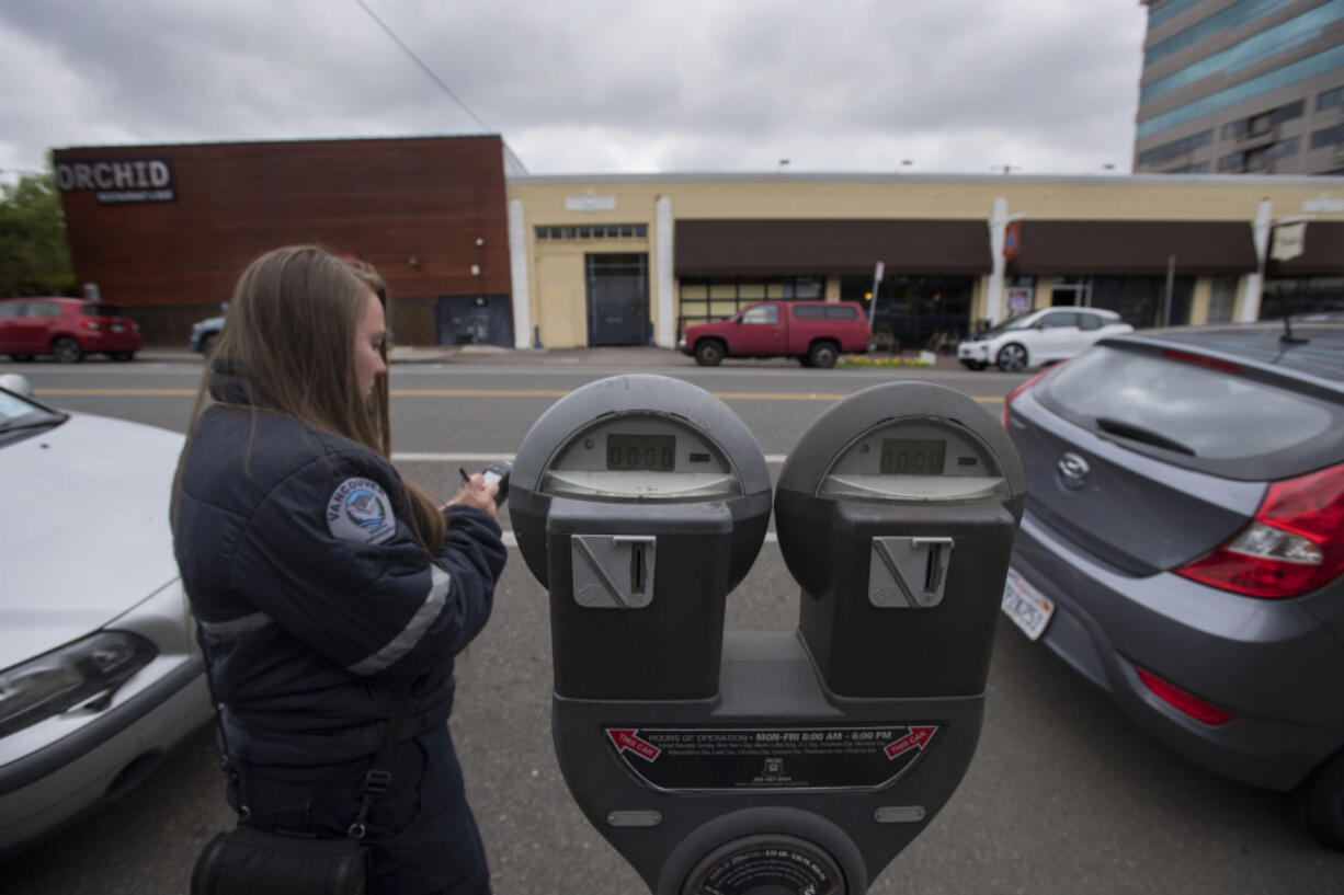 Parking enforcement officer Jessica Keenan tickets two vehicles, both for an expired meter, in downtown Vancouver on Thursday morning. Officers are writing more tickets than in the past five years.