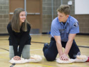 Annamarie Carlson, 14, listens to Fire District 3 cadet Seth Klinkhammer as he tells her how to perform CPR at Chief Umtuch Middle School in Battle Ground on Monday. Students learned how to perform hands-only CPR as part of a three-week health and fitness event.