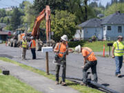 Amanda Cowan/The Columbian
Eric Levison, left in yellow vest, and Javier Moncada, second from left, of Otak, Inc., look on as crews begin construction on a year-long sewer expansion project, which will allow for growth north of Lacamas Lake in Camas.