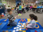 Kindergartners Chief Ben, 5, and Isabella Hernandez-Garcia, 6, use cards while learning three-dimensional shapes during class at Prune Hill Elementary School on April 13.