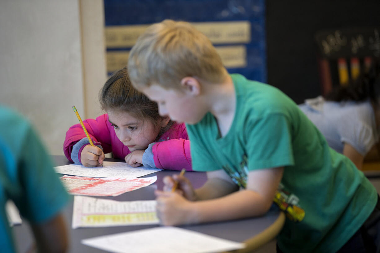 Amanda Cowan/The Columbian
First-grader Mariana Neal, left, keeps her focus on her schoolwork as classmate Max Miller attends to his own work at Washington Elementary School on Wednesday morning. Vancouver Public Schools will eliminate homework for K-3 students next year, instead encouraging families to do activities together.