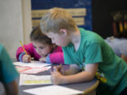 Amanda Cowan/The Columbian
First-grader Mariana Neal, left, keeps her focus on her schoolwork as classmate Max Miller attends to his own work at Washington Elementary School on Wednesday morning. Vancouver Public Schools will eliminate homework for K-3 students next year, instead encouraging families to do activities together.