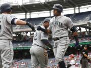 Seattle Mariners Nelson Cruz, right, celebrates with teammates, Kyle Seager, left, and Jean Segura (2) after hitting a three-run home run during the sixth inning of a baseball game against the Washington Nationals in Washington, Thursday, May 25, 2017. The Mariners won 4-2.