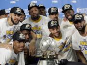 Golden State Warriors' JaVale McGee, top left, Kevin Durant, top center, Stephen Curry, center right, and Draymond Green, top right, join the rest of their team as they pose with the trophy after their 129-115 win over the San Antonio Spurs in Game 4 of the NBA basketball Western Conference finals, Monday, May 22, 2017, in San Antonio.