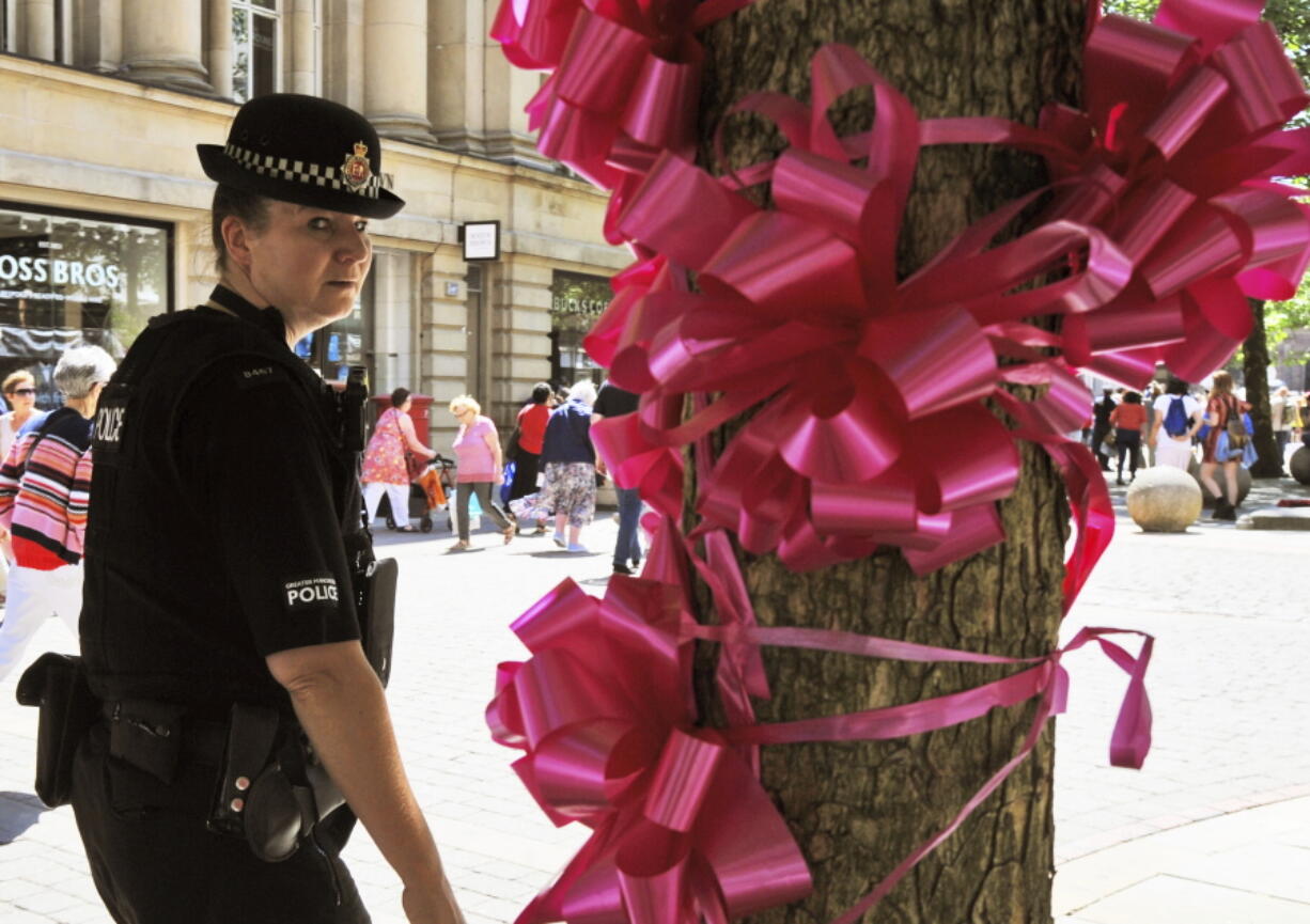 Police patrol past a pink ribbon tribute in central Manchester, England, on Friday. More than 20 people were killed in an explosion following a Ariana Grande concert at the Manchester Arena late Monday evening.