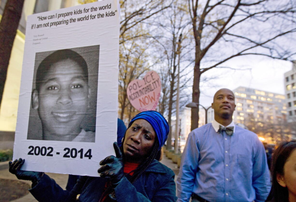 In this Dec. 1, 2014, file photo, Tomiko Shine, left, holds a sign with a photo of Tamir Rice, a boy fatally shot by a Cleveland police officer, while protesting a grand jury's decision in Ferguson, Mo., not to indict police officer Darren Wilson in the shooting death of Michael Brown, during a demonstration in Washington. Cleveland Police Chief Calvin Williams announced Tuesday, May 30, 2017, that Timothy Loehmann, the police officer who shot and killed the 12-year-old boy, has been fired for inaccuracies on his job application, while the officer who drove the patrol car the day of the Nov. 22, 2014, shooting, Frank Garmback, has been suspended for 10 days for violating a tactical rule for his driving that day.