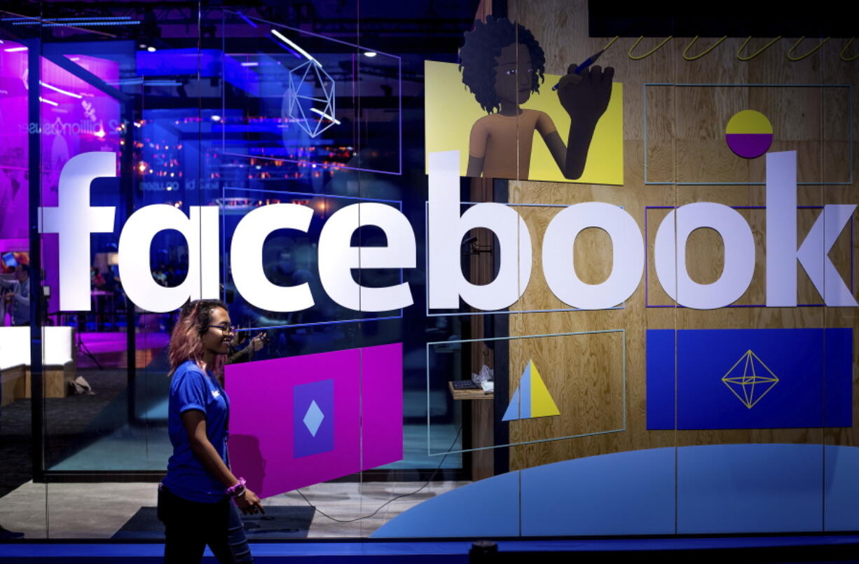 A conference worker passes a demo booth at Facebook&#039;s annual F8 developer conference April 18, in San Jose, Calif.