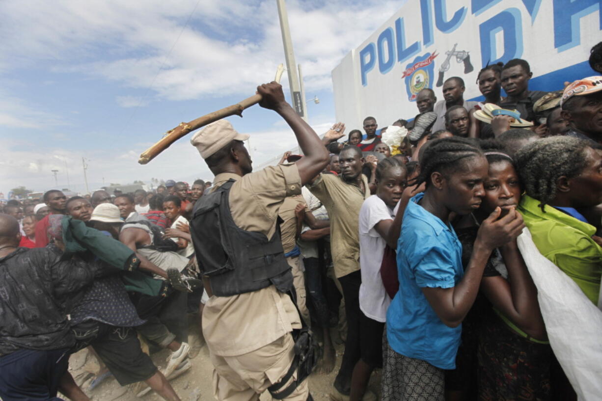 Haitian police use sticks to try and keep the crowd in order at a food distribution point in the Cite Soleil neighborhood in the aftermath of the Jan. 12 earthquake in Port-au-Prince on Jan. 26, 2010.