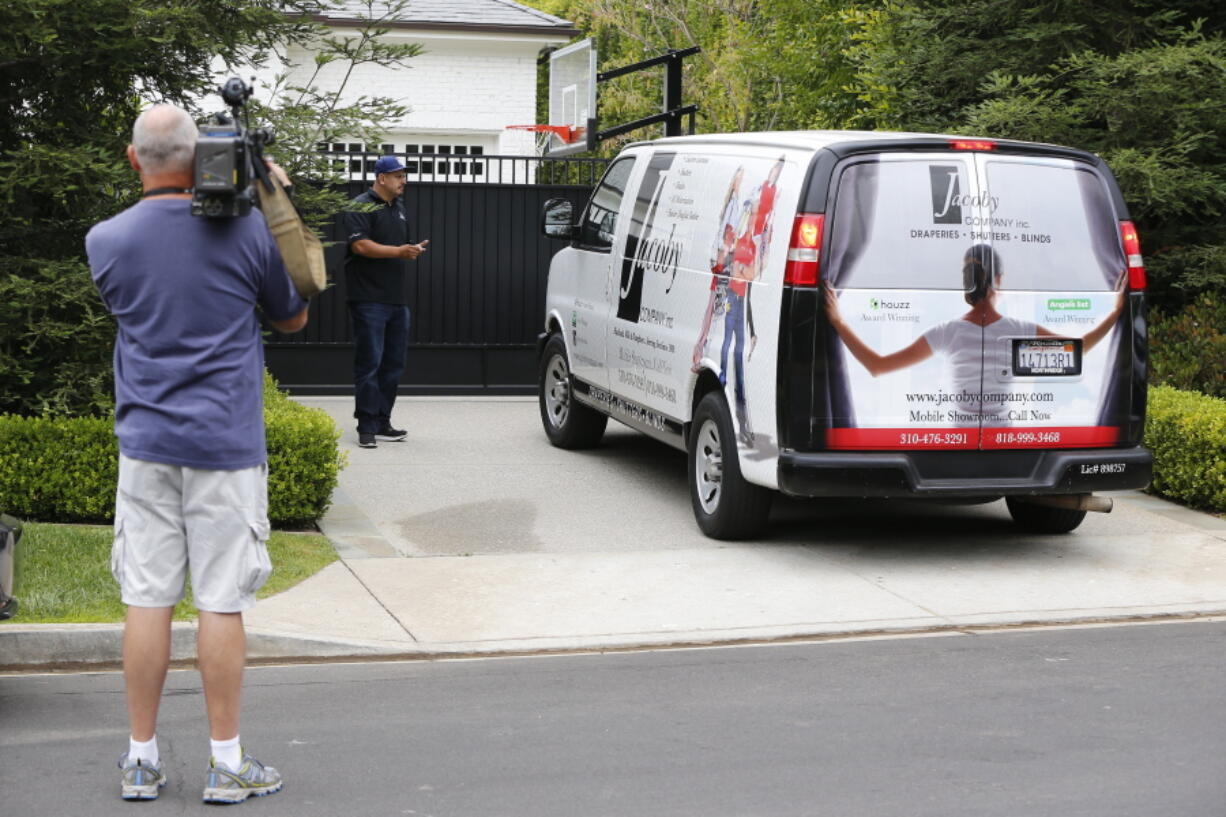 A television cameraman shoots video Wednesday across from the front gate of a home belonging to Cleveland Cavaliers’ LeBron James in Los Angeles. Police are investigating after someone spray-painted a racial slur on the front gate of James’ home in Los Angeles on the eve of the NBA Finals.